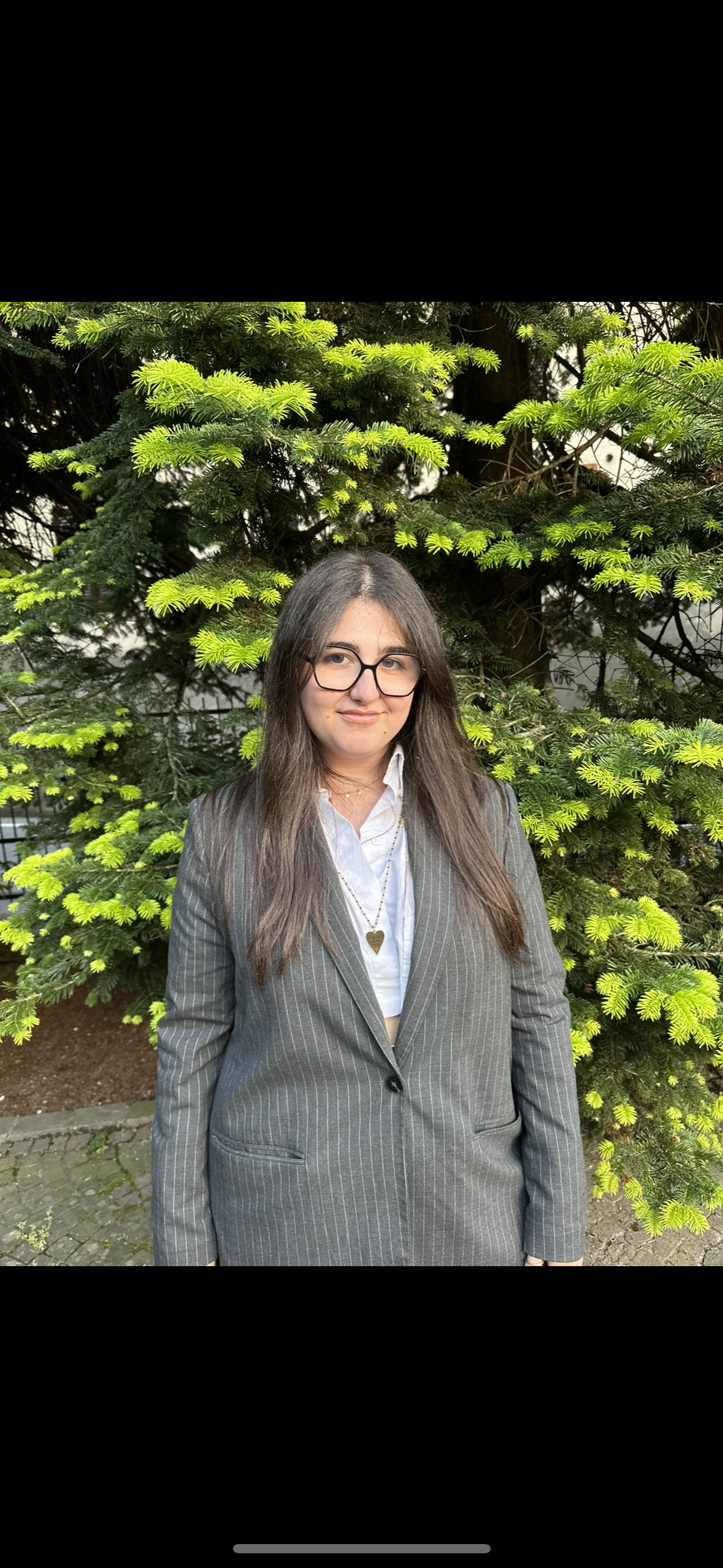 Portrait of a man with brown hair and glasses on a flat gray background.